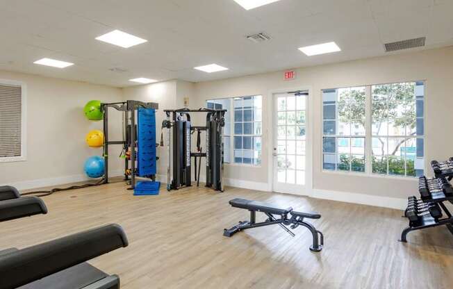 A gym with a variety of equipment including a bench, weights, and a ball.