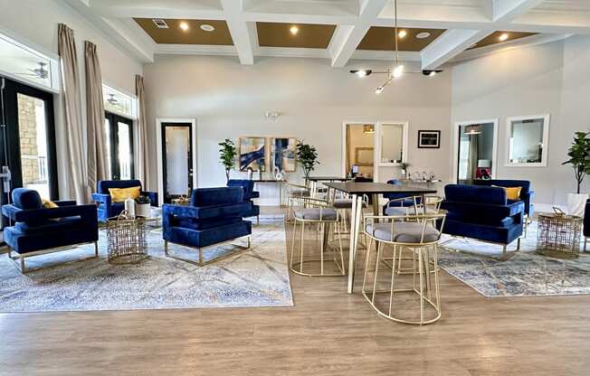 a living room with blue chairs and tables and a kitchen