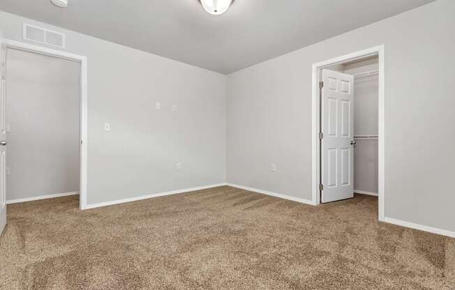A room with carpeted floor and two doors.