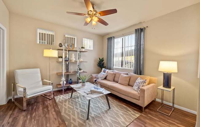 Living room with windows and casual comfortable furniture at The Fairways by Picerne Apartments, Las Vegas, NV