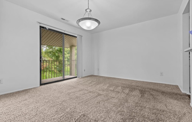 an empty living room with a sliding glass door to a patio at Edge At Farmington Hills - Farmington Hills, MI, Farmington Hills, Michigan