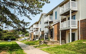 a sidewalk leading to a row of townhomes with balconies