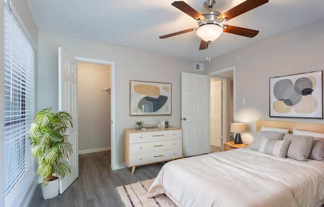 A bedroom with a bed, dresser, and ceiling fan.