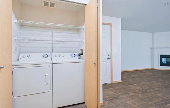 A full size washer and dryer in the York floorplan with the living room in the background at Abbey Rowe Apartments in Olympia, WA