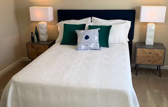 A bed with a white comforter and green pillows is in the image.