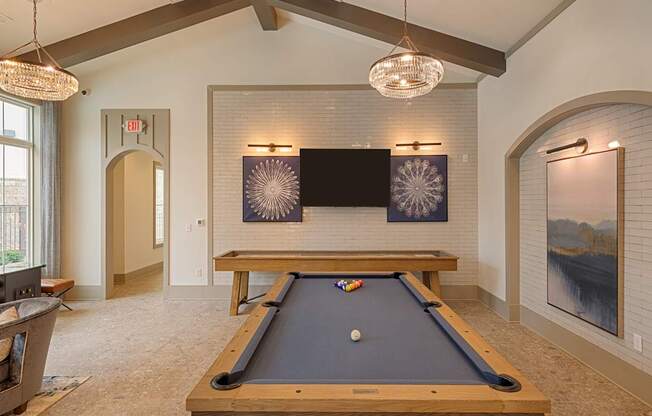 A pool table is in the middle of a room with a television and a fireplace.