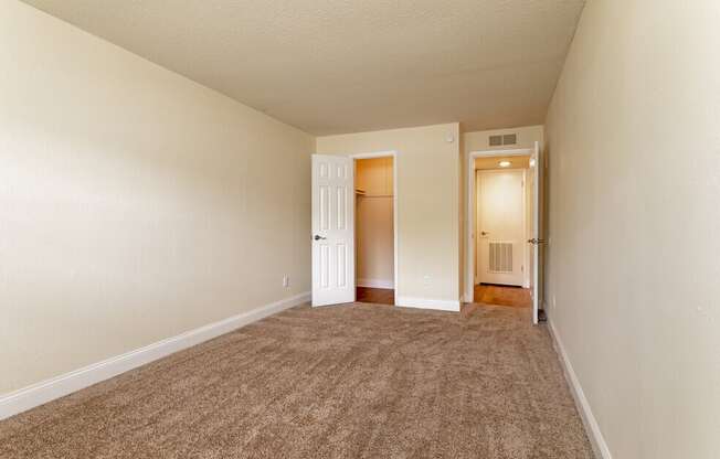 A room with carpeted floor and two doors.