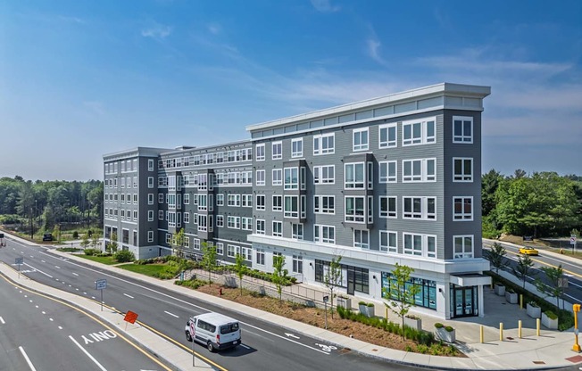 A modern multi-story building with a parking lot in front.