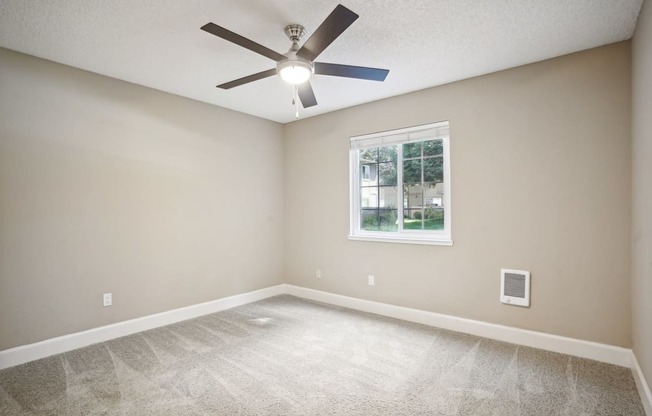 an empty living room with a ceiling fan and a window