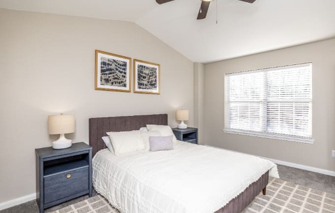 A bedroom with a bed, two lamps, and two pictures on the wall.