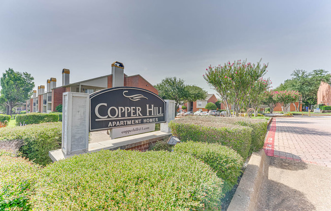 A sign for Copper Hill Apartment Homes is in front of a building at Copper Hill Apartments, Bedford, TX