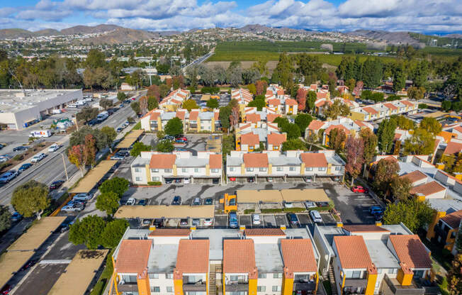 an aerial view of a neighborhood with orange roofs and a green field in the background