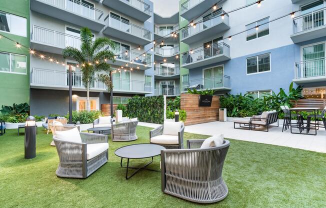 The landscaped courtyard features outdoor lounge seating, gathering spaces, and open green areas that provide a welcoming setting for socializing, relaxing, and enjoying the outdoors.