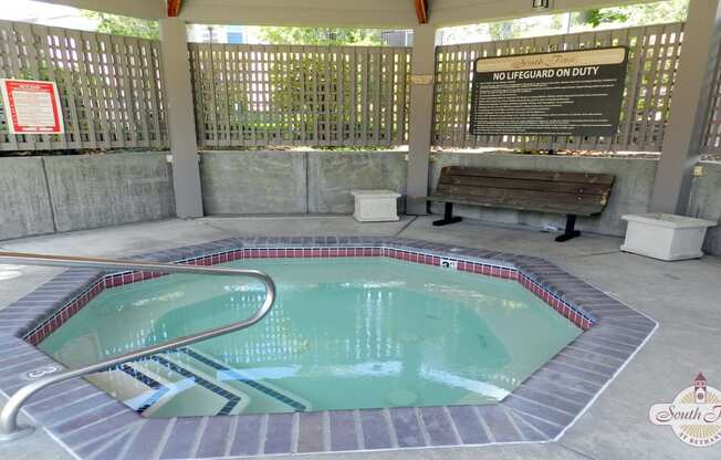 a swimming pool in a pavilion with a bench next to it