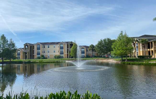 View of lake with fountain in the middle and building exteriors in the background