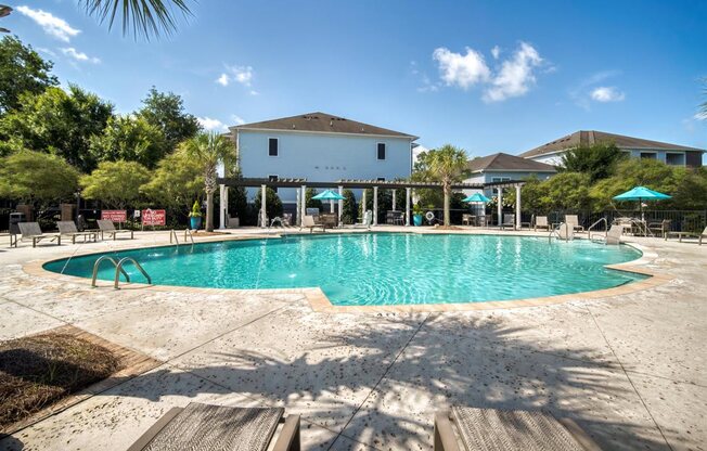 A large swimming pool in front of a building with a white fence around it.