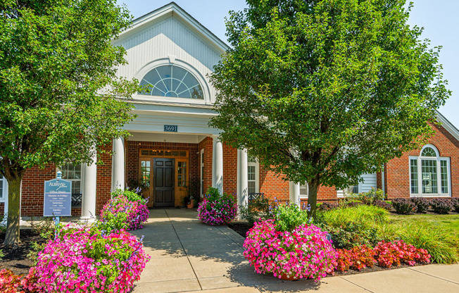 the front of a brick building with flowers and trees