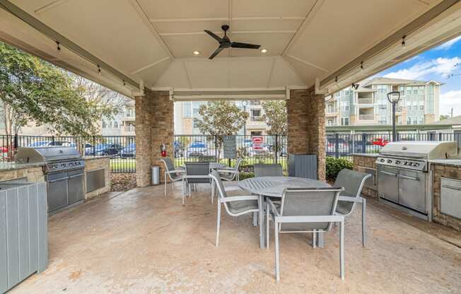 a patio with a table and chairs and a grill