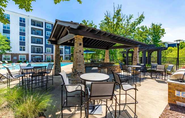 a patio with tables and chairs and a pavilion with a pool and a building