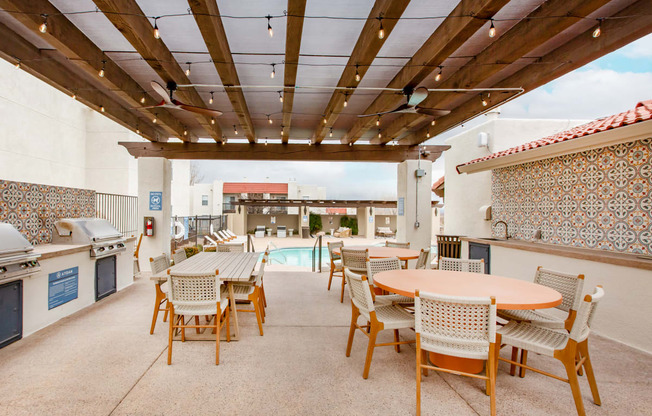a patio with tables and chairs and a pool in the background