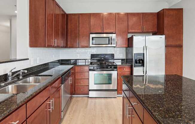 A kitchen with brown cabinets and a black countertop.