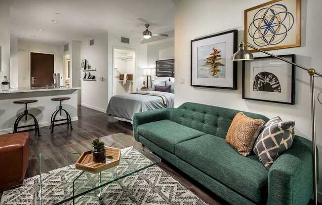 A living room with a green couch and a glass coffee table.