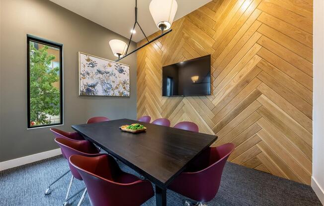 A resident conference meeting room with a table, 8 chairs, a TV, and a window.