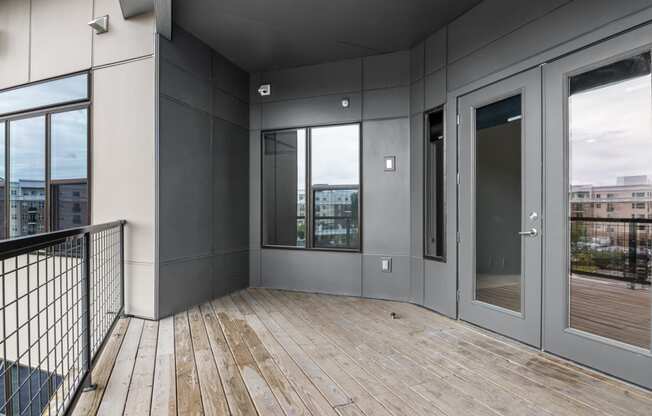 the view from the balcony of an apartment with wood floors and glass doors