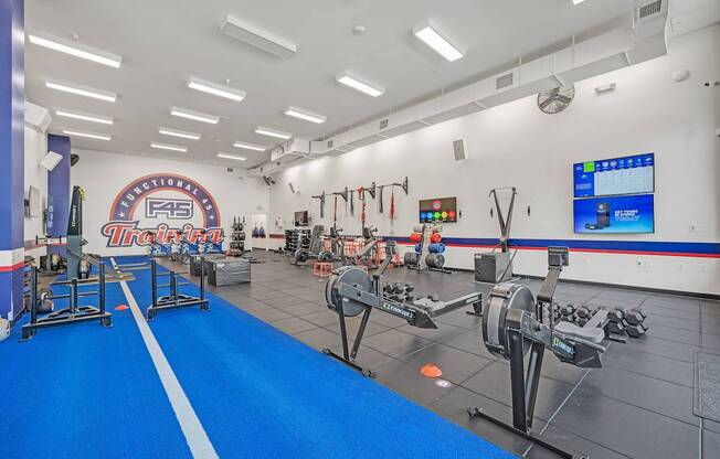A gym with a blue floor and a white wall with a screen on it.
