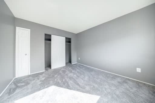 a bedroom with grey walls and white carpet