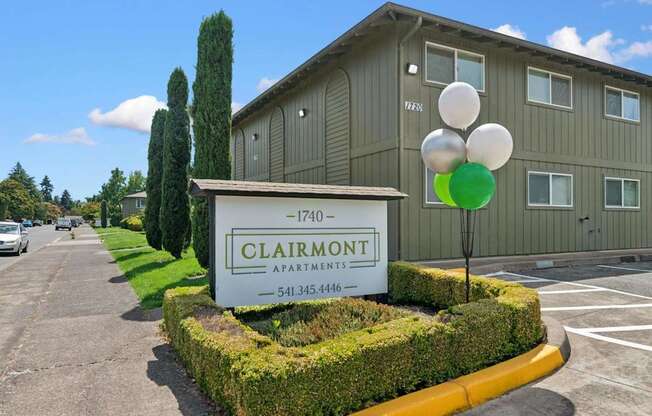 A sign for Clairmont Apartments is in front of a building.