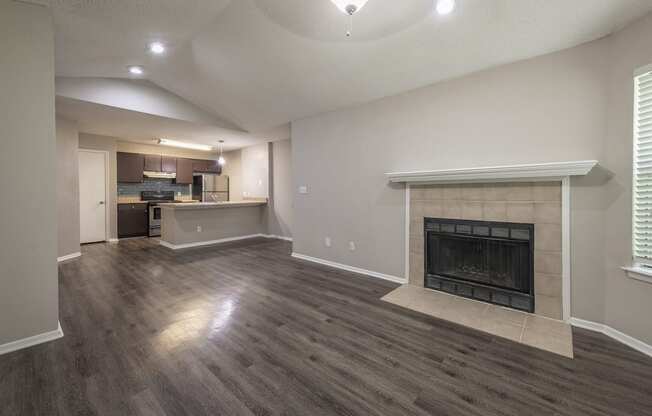 a living room with a fireplace and a kitchen in the background