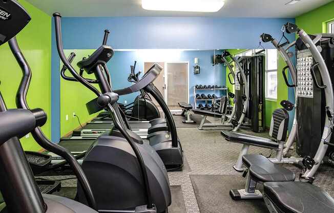 A gym with exercise equipment and a green wall.