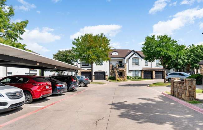 Covered parking area with carports, garages, and landscaped apartment buildings at Villas of Vista Ridge.