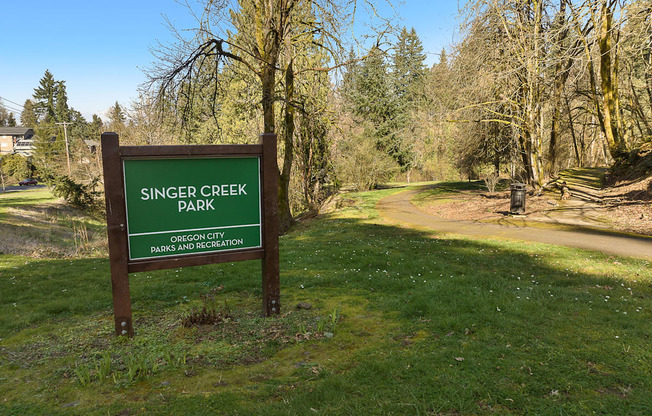 a sign for singer creek park next to a dirt road