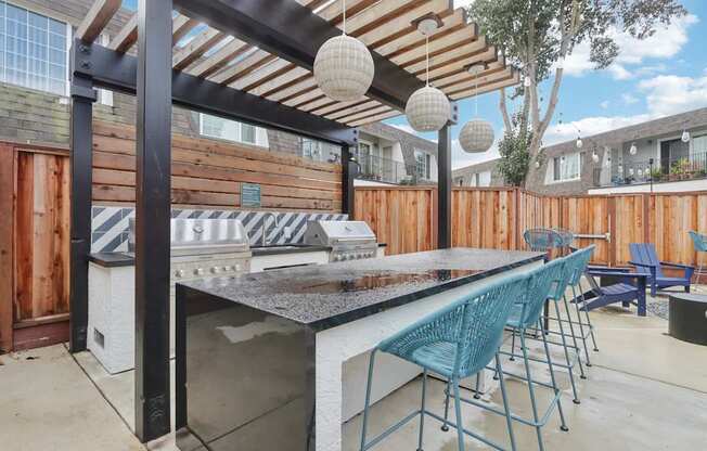 A patio with a bar and chairs under a pergola.