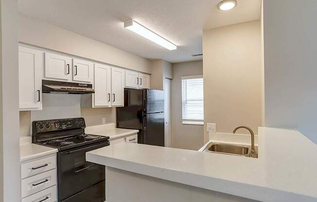 A kitchen with white cabinets and a black stove top oven.
