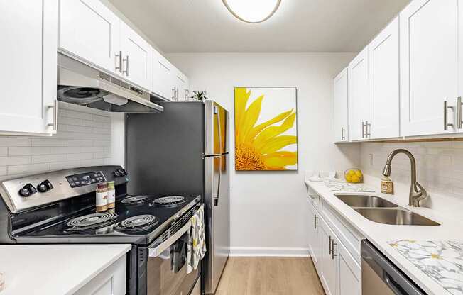 A kitchen with a black refrigerator and a yellow painting on the wall.
