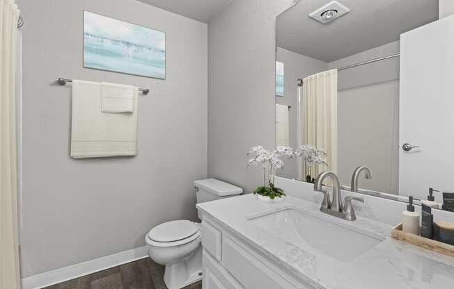 a white bathroom with a large mirror and a toilet and sink