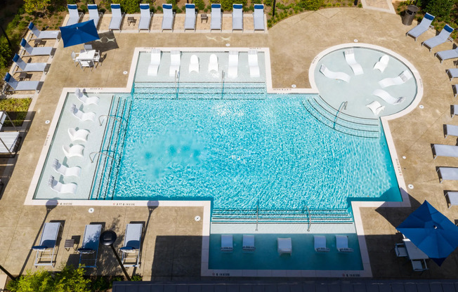 Aerial photograph of the pool area at our apartments in Atlanta, featuring pool chairs, reclining chairs, and umbrellas.