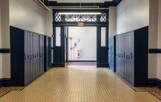 a hallway with rows of lockers and doors in a building at Residences at South High, Pittsburgh, 15203 ? 