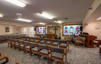 a church with chairs and a piano and a stained glass window