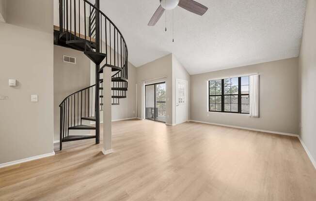 A spacious room with a spiral staircase and a ceiling fan.