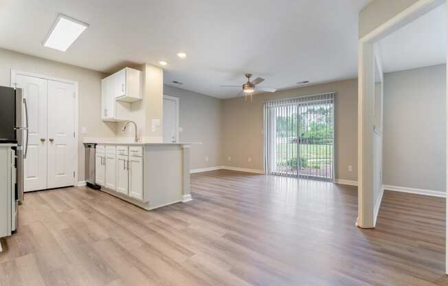 an open kitchen and living room with a sliding glass door to a balcony