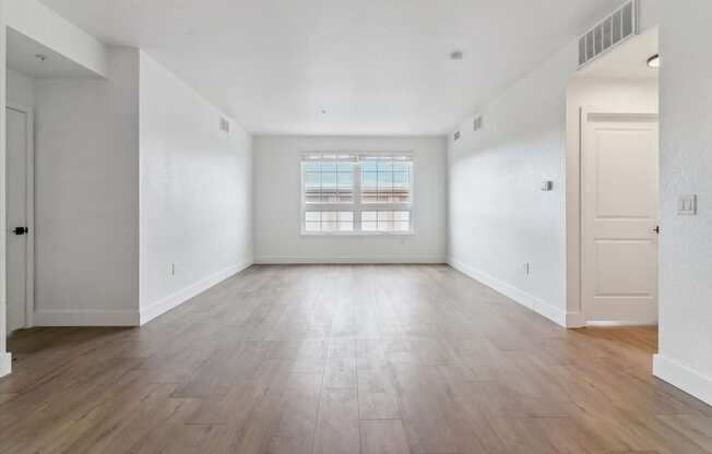 an empty living room with white walls and wood floors