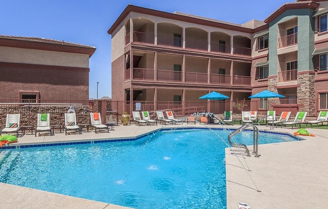 Sparkling swimming pool surrounded by lounge chairs, patio tables and blue umbrellas