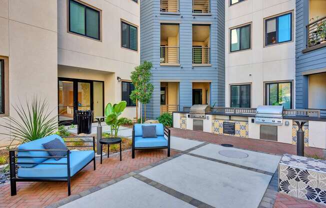 A patio with a blue couch and a table with a plant on it.