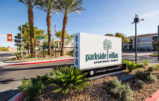 A sign for Parkside Villas Apartment Homes is in front of a palm tree.