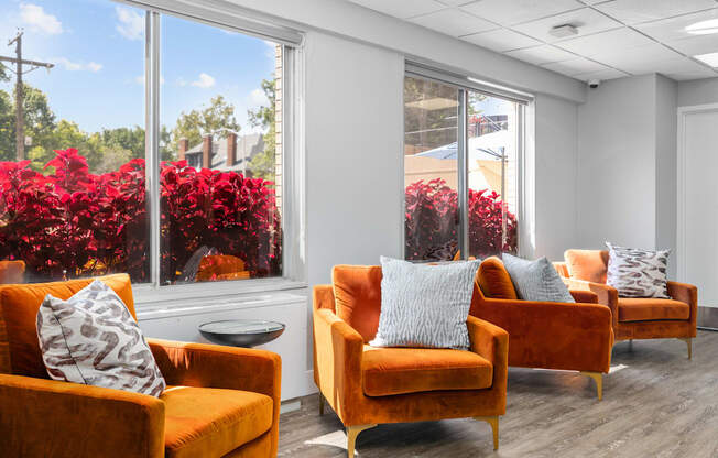 a seating area with orange chairs and red flowers in the background