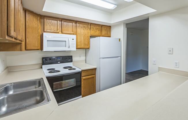 an empty kitchen with white appliances and wooden cabinets